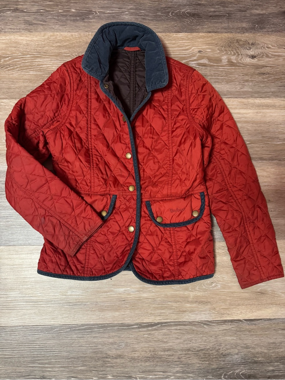 Girls Barbour Red Quilted Jacket with Navy Trim and adjustable back.